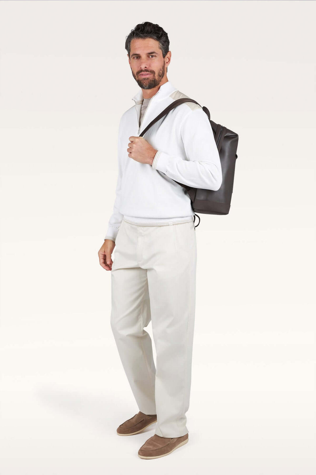 Homme portant un chandail à demi-zip blanc avec un sac à dos, silhouette moderne et décontractée chic. Décris moi le produit en français.