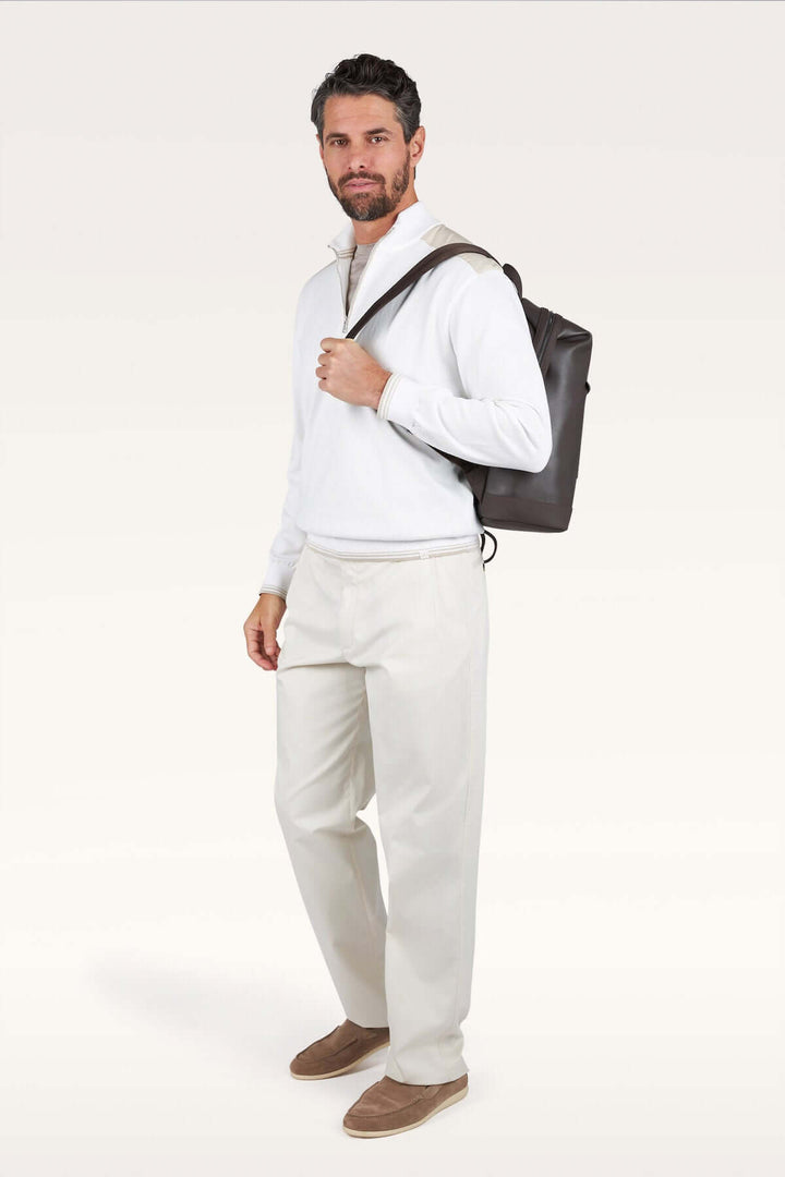 Homme portant un chandail à demi-zip blanc avec un sac à dos, silhouette moderne et décontractée chic. Décris moi le produit en français.