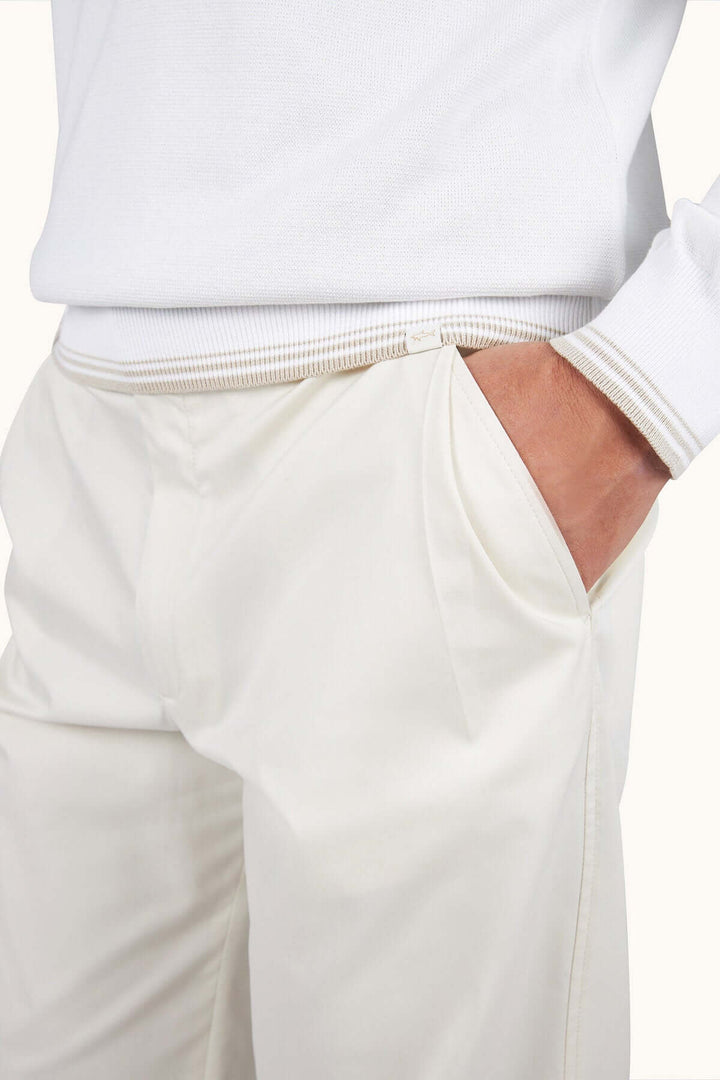 Personne portant un chandail à demi-zip moderne blanc et pantalon assorti pour un look chic décontracté.