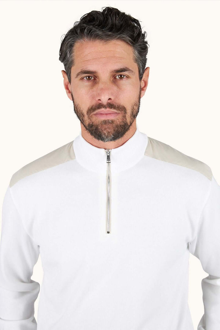 Homme portant un chandail à demi-zip blanc avec col montant et demi-fermeture éclair, style décontracté chic et coupe droite confortable.