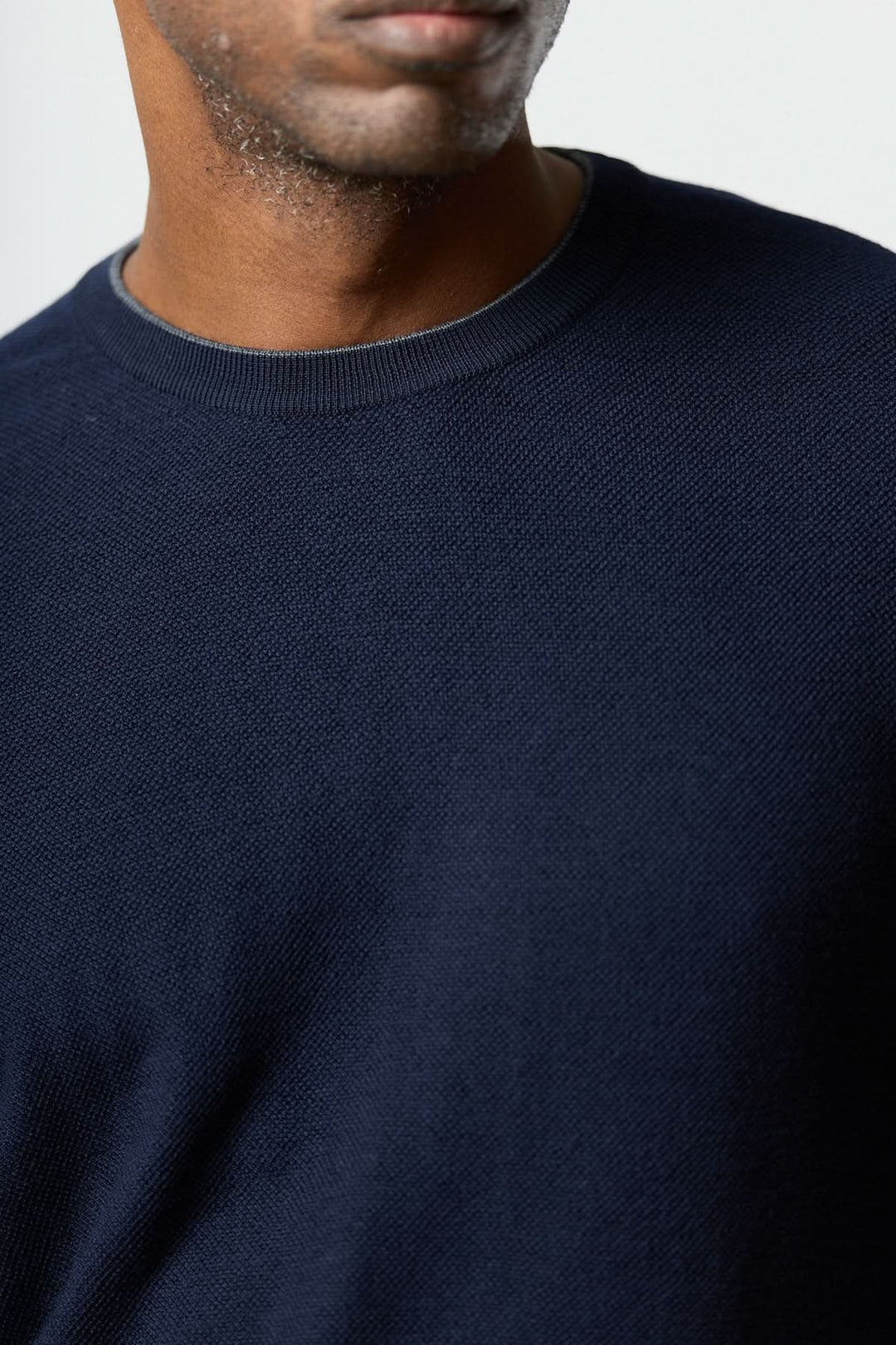 Homme portant un chandail en laine à col rond couleur bleu marine, confectionné par Corneliani, montrant une texture fine et ajustée.