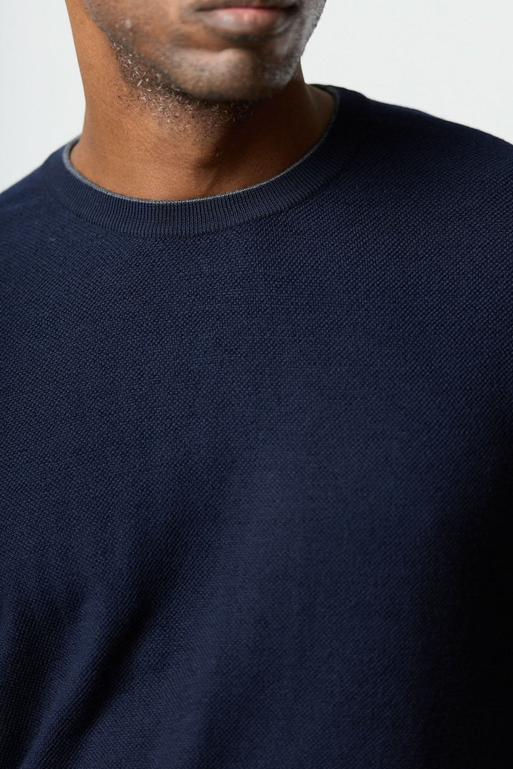 Homme portant un chandail en laine à col rond couleur bleu marine, confectionné par Corneliani, montrant une texture fine et ajustée.