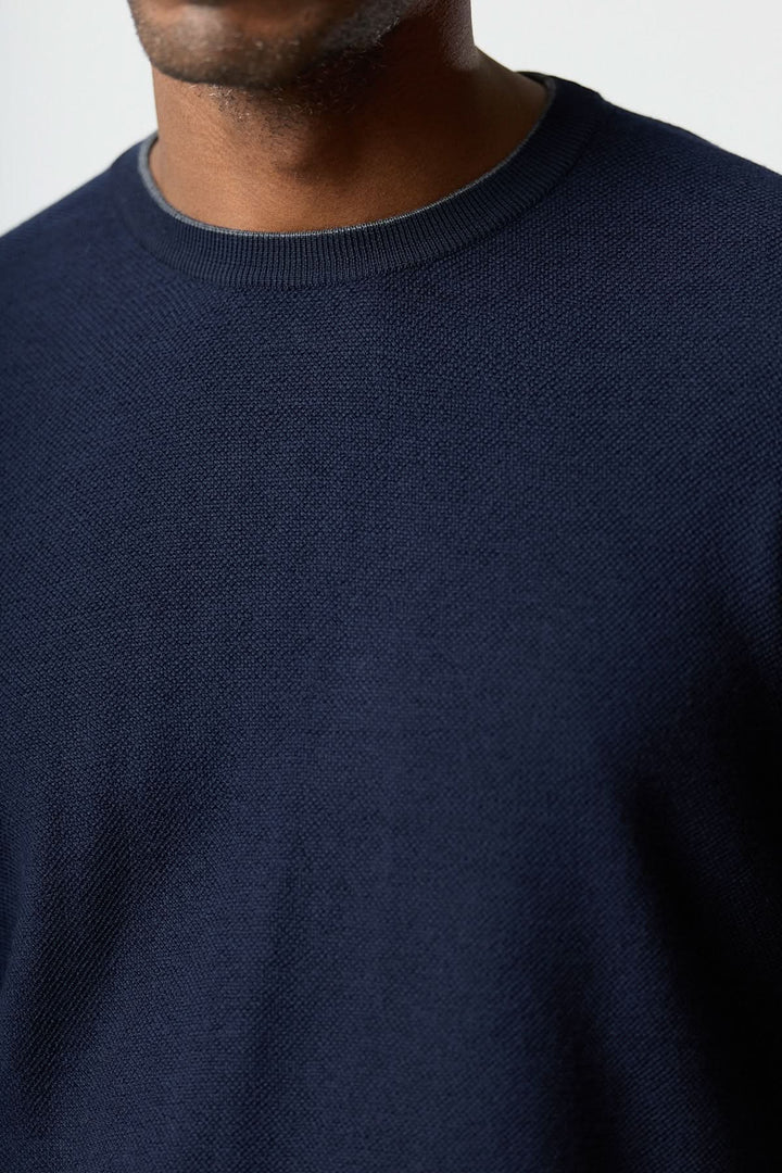 Homme portant un chandail en laine à col rond Corneliani, couleur bleue, texture fine, finition élégante, mise en valeur de la silhouette.