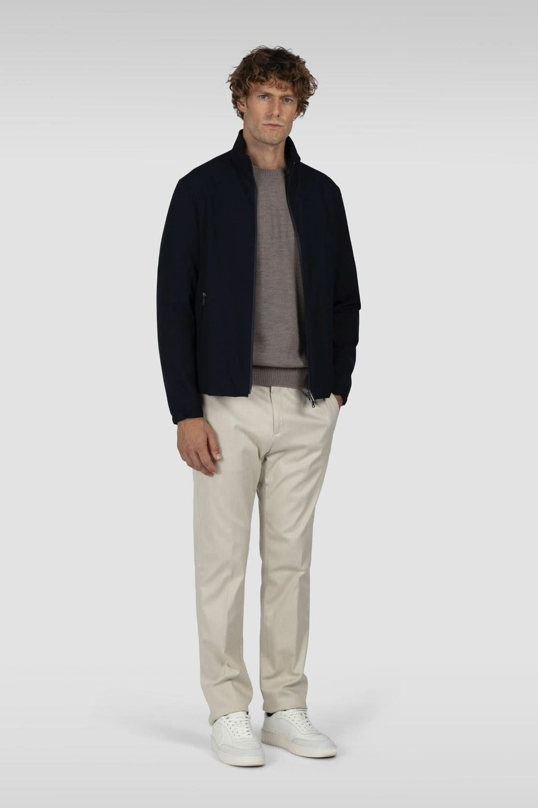 Homme portant un chandail en laine mérinos avec empiècements côtelés, veste noire et pantalon beige, style décontracté élégant.