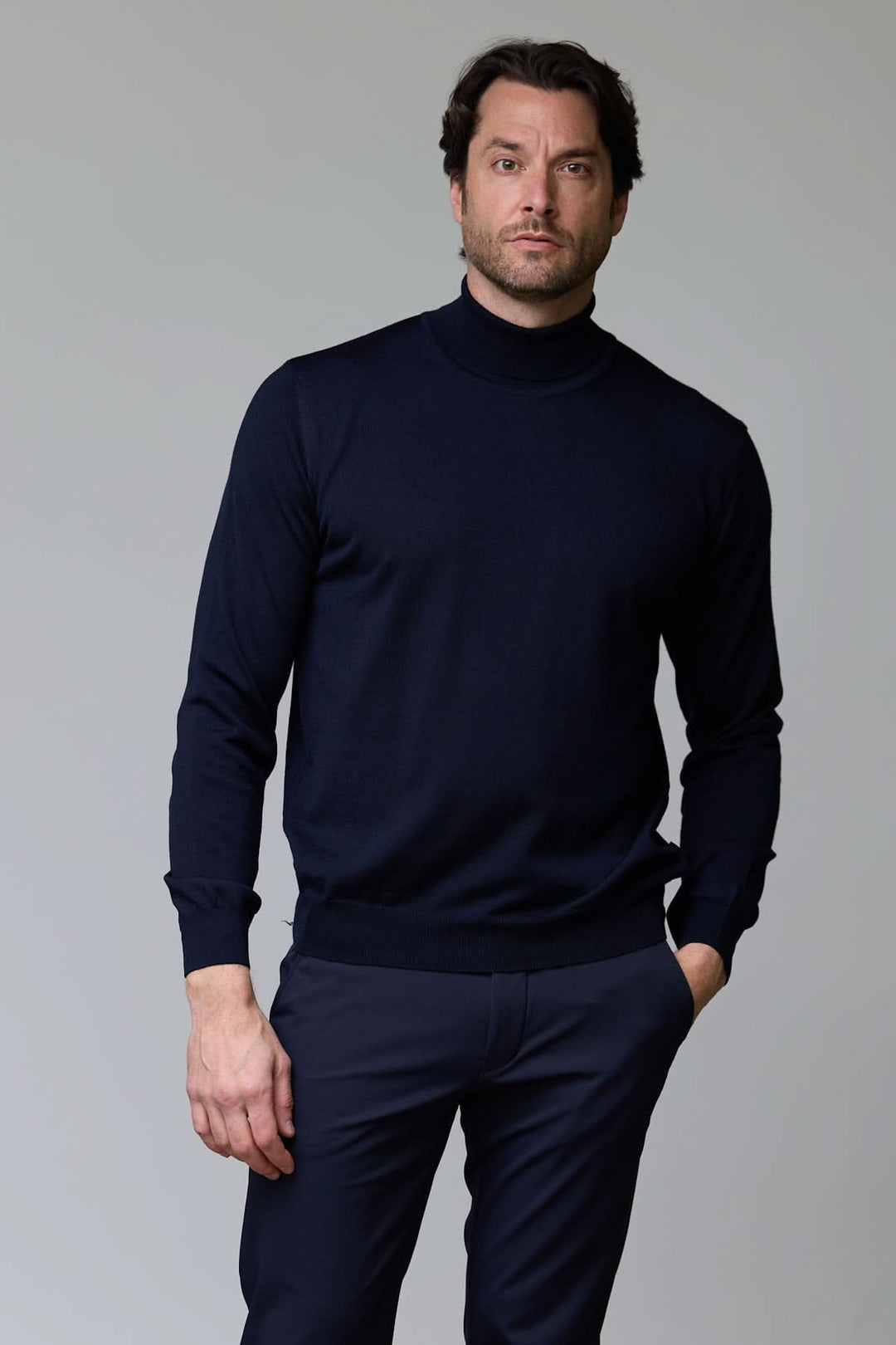 Homme portant un chandail en laine mérinos fine bleu foncé avec col rond et bordure côtelée pour un look élégant et intemporel.