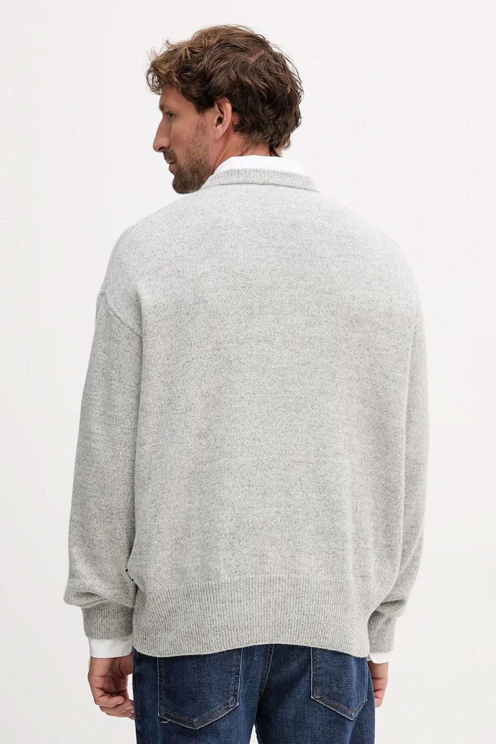 Homme portant un chandail en laine vierge coupe "oversize" de couleur grise, vue de dos. Décris moi le produit en français.