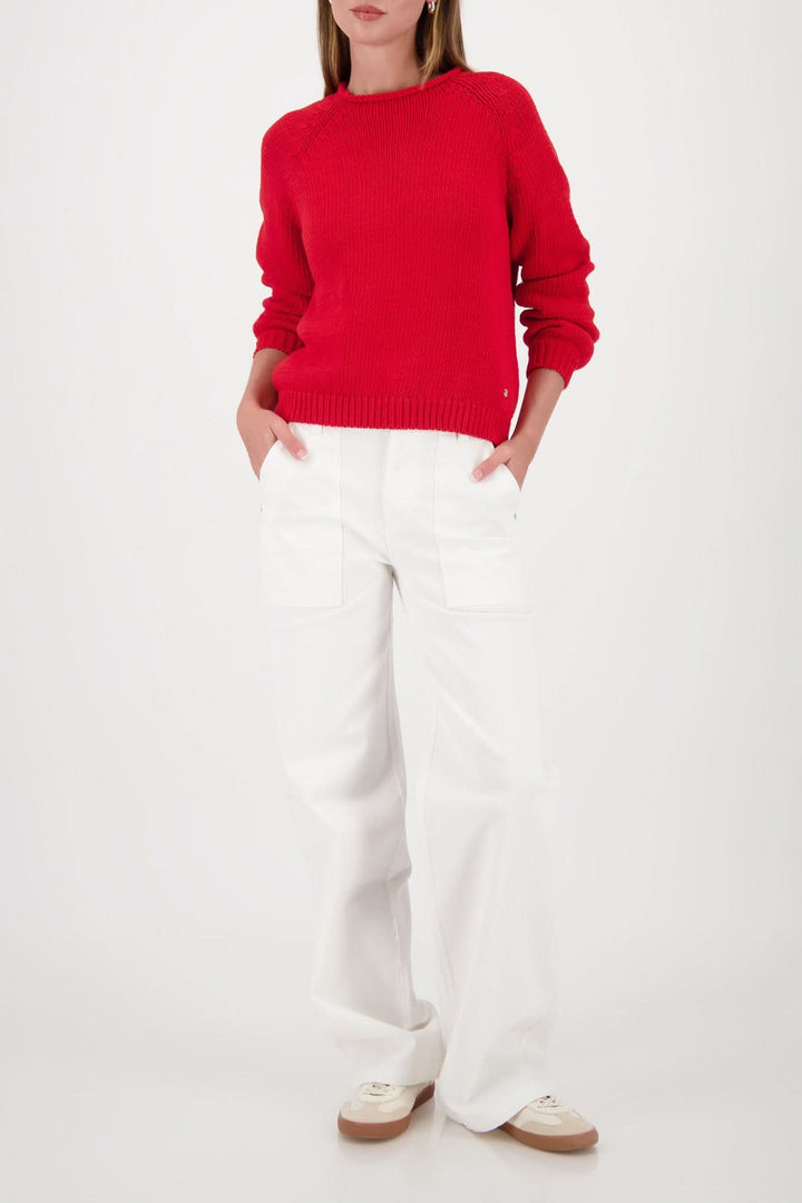 Chandail en maille col rond rouge porté avec un pantalon blanc pour un look décontracté et moderne.