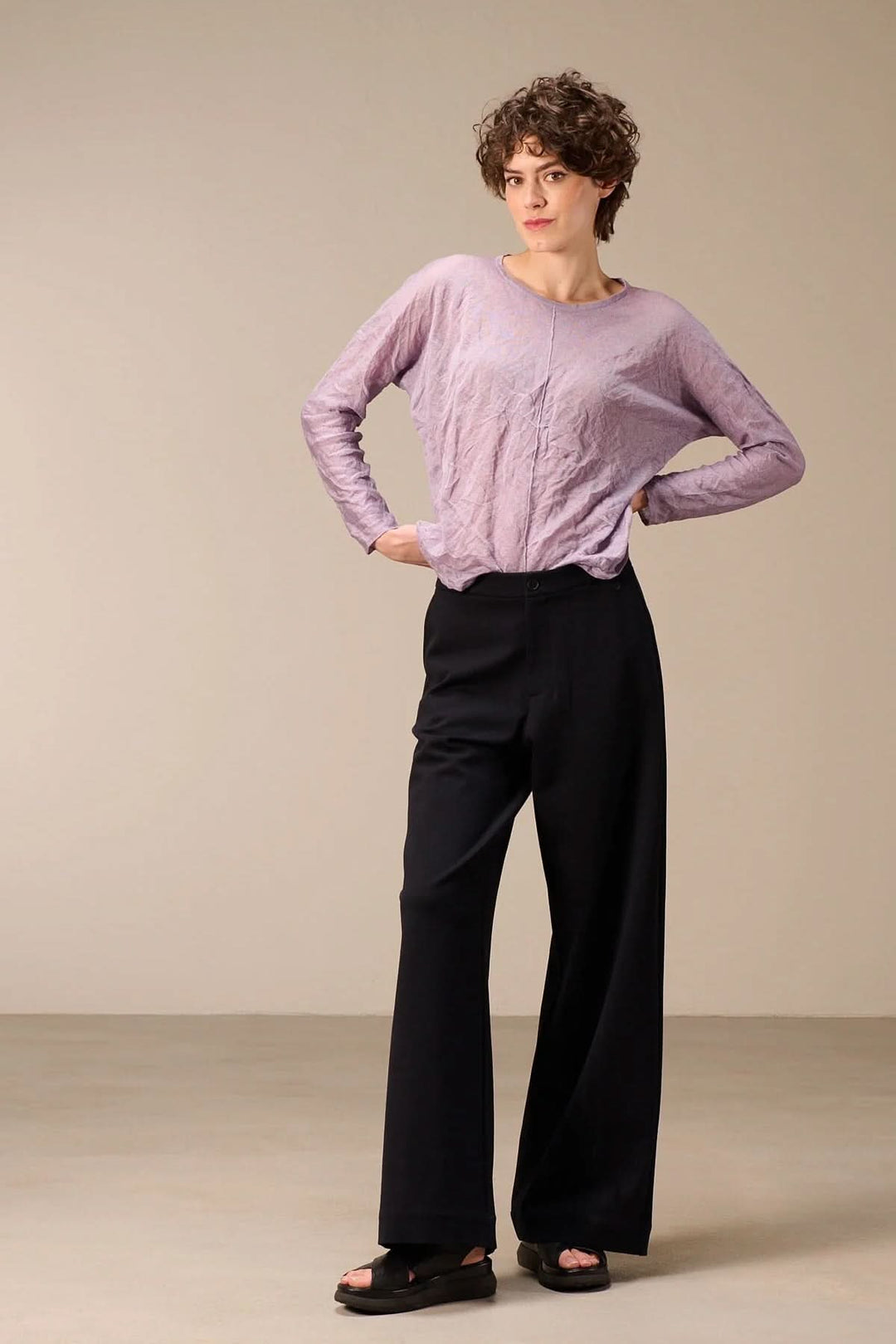 Femme portant un chandail en maille fine lilas avec une texture froissée, coupe droite, idéal pour un look décontracté et moderne.