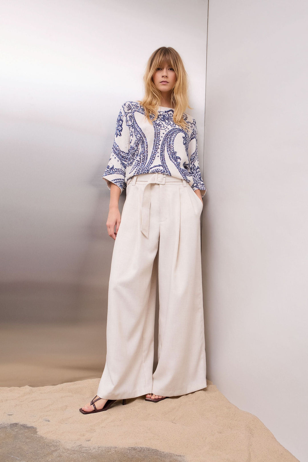 Femme portant un chandail en maille à motif cachemire avec manches trois-quarts, style moderne et fluide, sur pantalon clair.