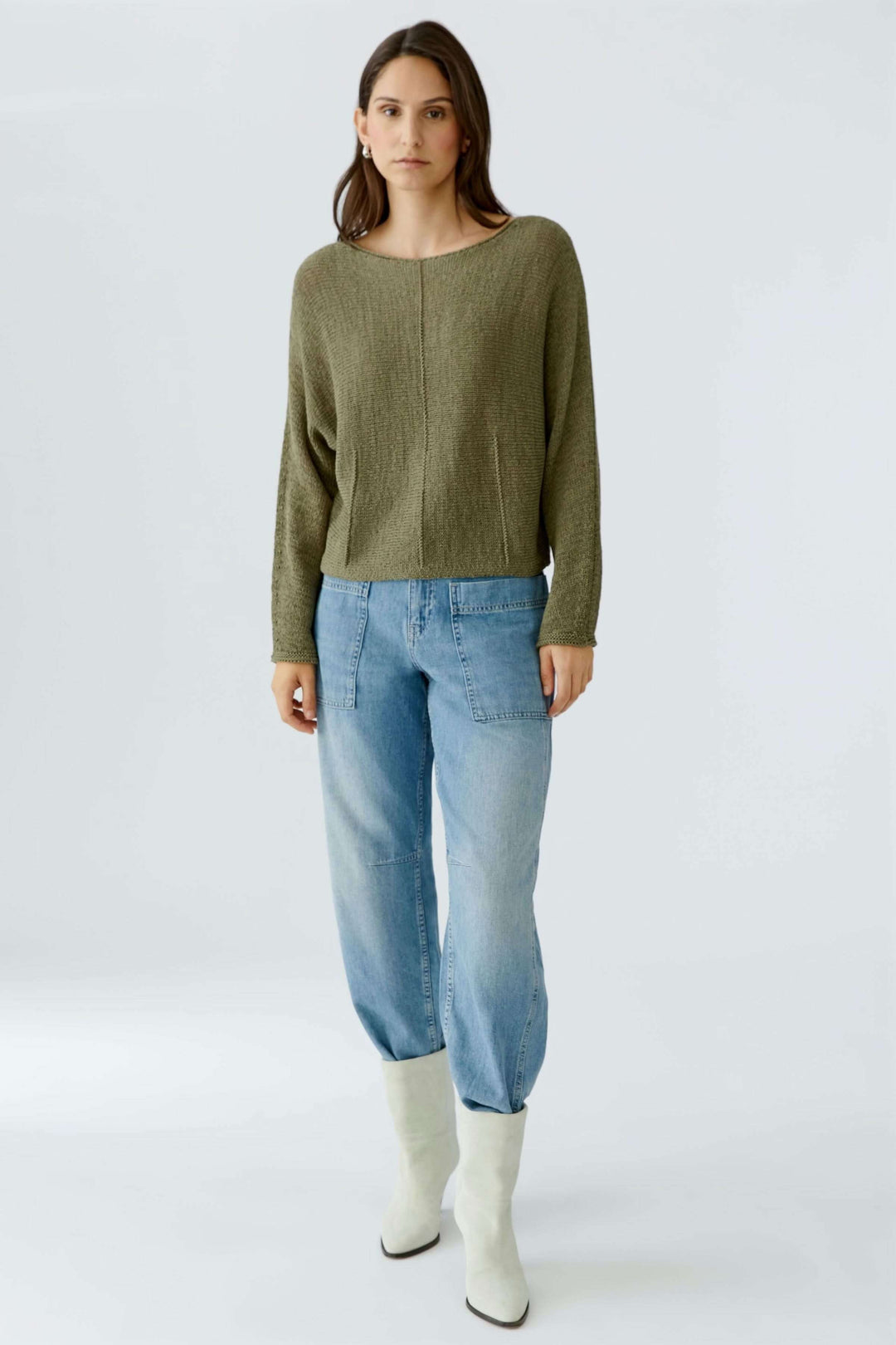 Femme portant un chandail en ruban tricoté avec un jean et des bottes blanches, style décontracté et moderne.