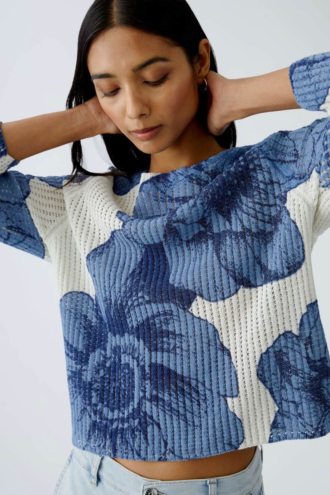 Femme portant un chandail en tricot côtelé à motif floral bleu, coupe décontractée, encolure ronde.