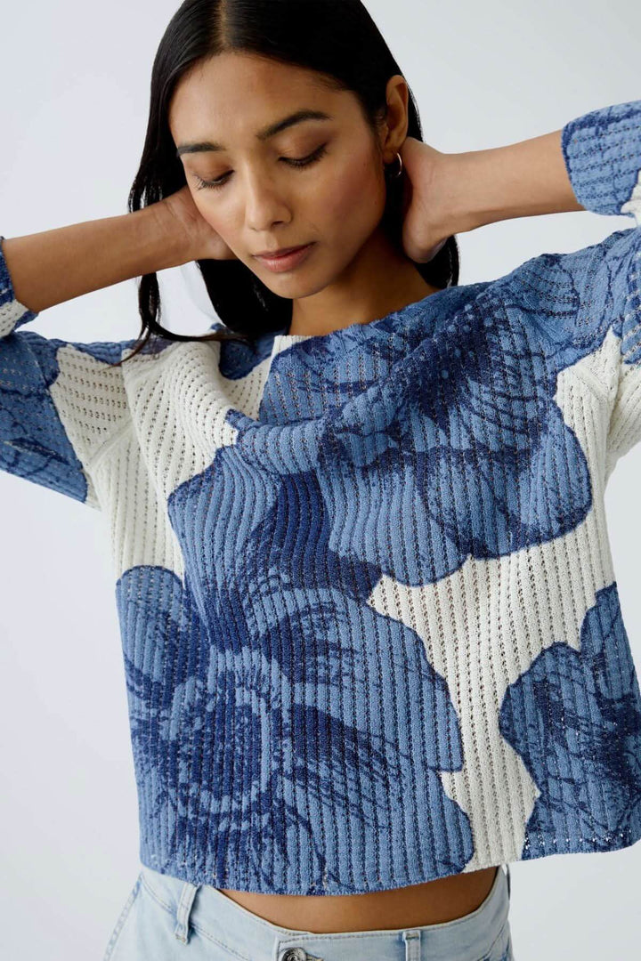 Femme portant un chandail en tricot côtelé à motif floral bleu, coupe décontractée, encolure ronde.