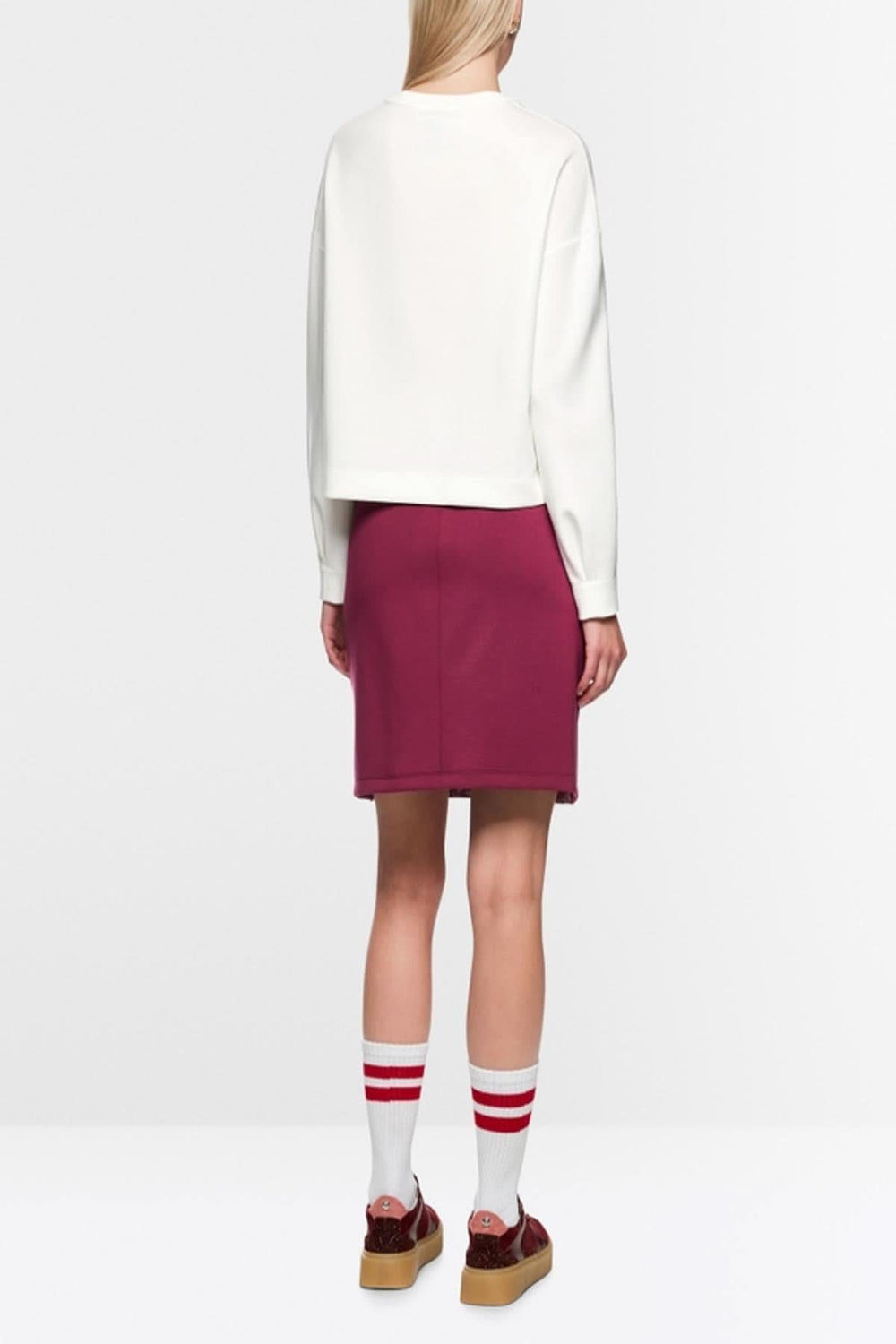 Vue arrière d'un mannequin portant un chandail en tricot blanc avec jupe bordeaux, de dos, mettant en avant le style moderne et structuré.