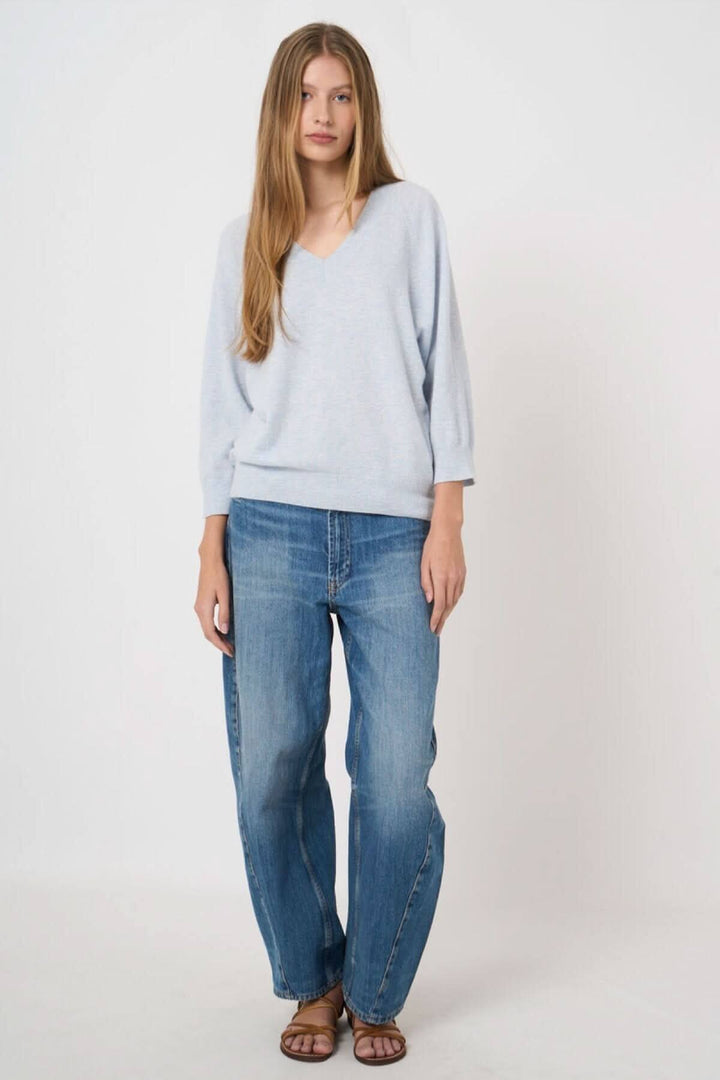 Femme portant un chandail en tricot à col en V, avec un look décontracté et élégant.