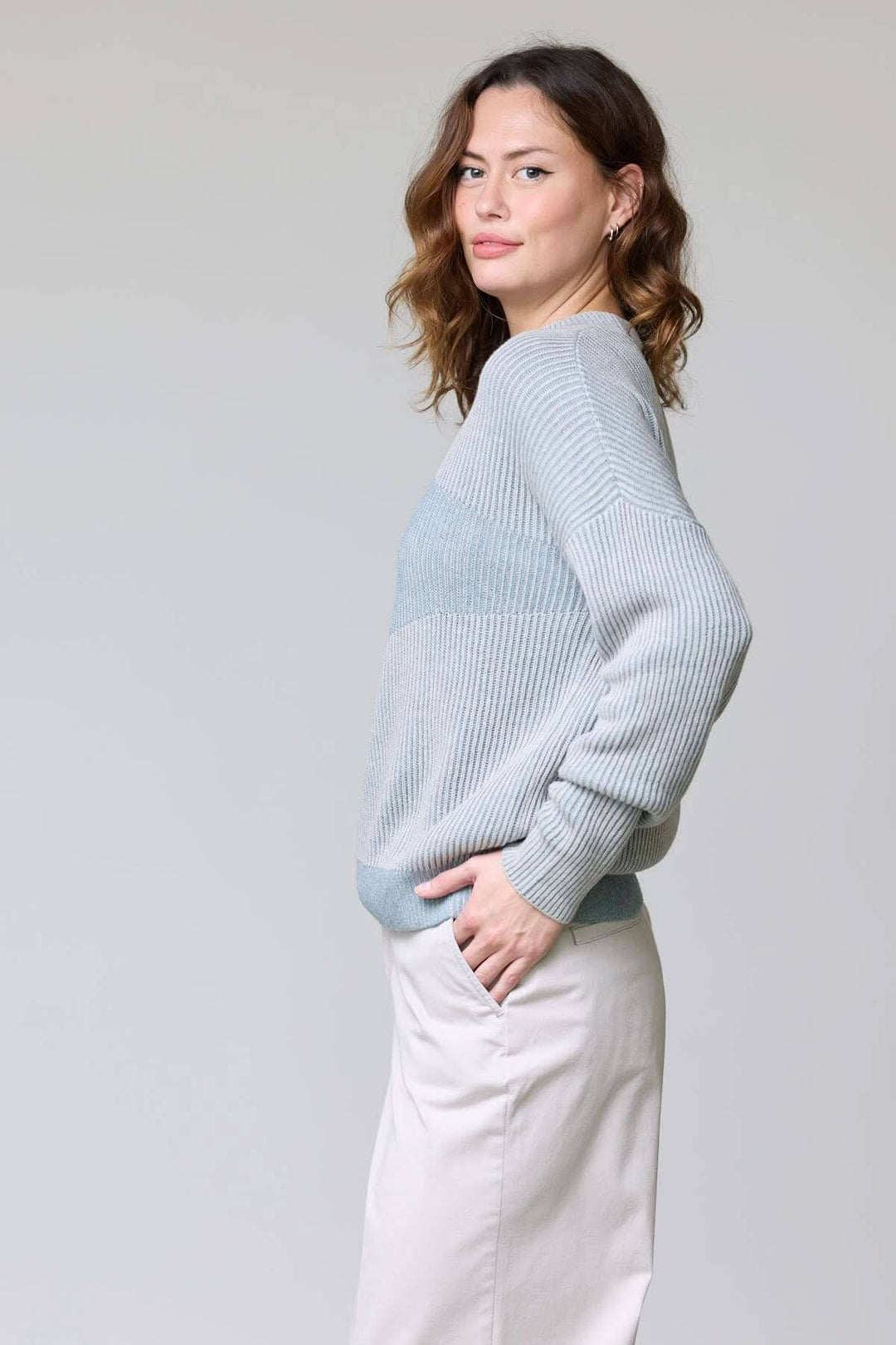 Femme portant un chandail en tricot côtelé bleu avec coupe décontractée et finition raffinée. Tissu léger et respirant, style moderne.