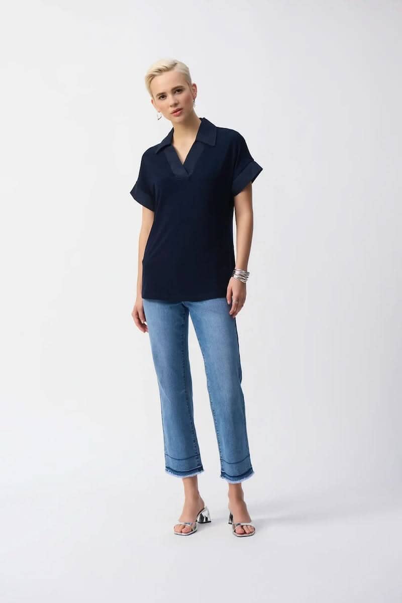 Femme portant un chandail en tricot soyeux avec un col ouvert et un pantalon en jean, style décontracté.
