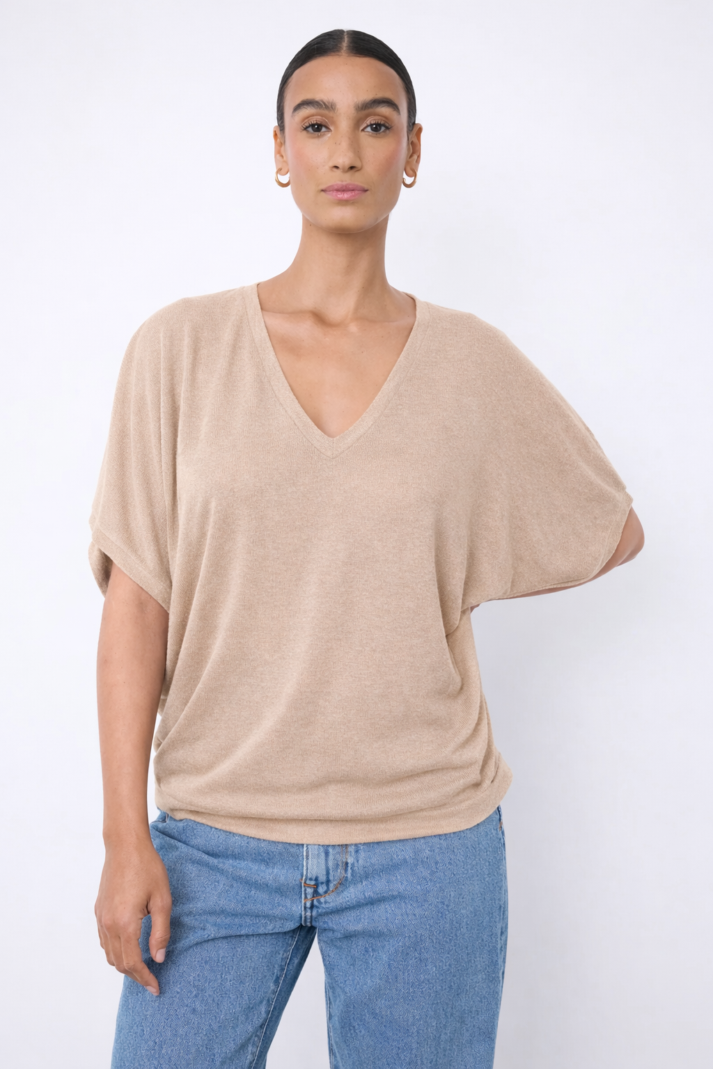 Chandail à encolure en V beige, manches courtes larges, maille légère, porté avec jean par une personne.