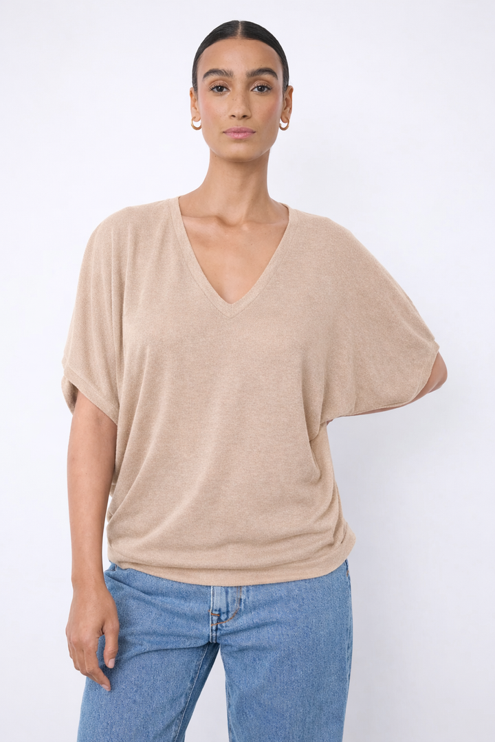 Chandail à encolure en V beige, manches courtes larges, maille légère, porté avec jean par une personne.