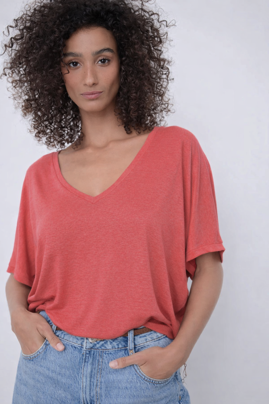 Femme portant un chandail à encolure en V rouge, silhouette fluide et décontractée, manches courtes larges, maille légère.