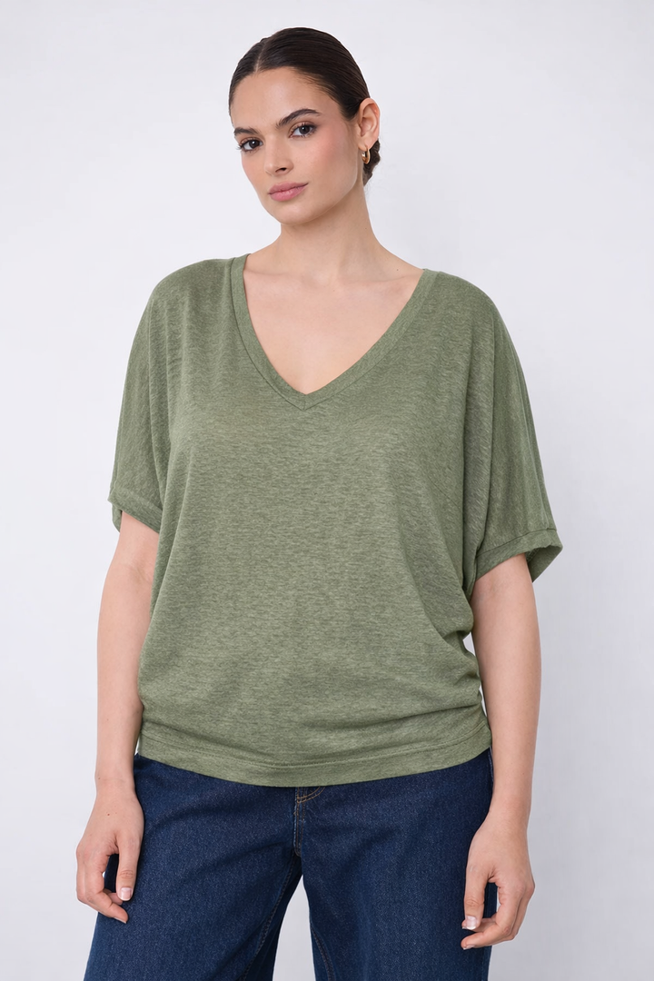 Femme portant un Chandail à encolure en V vert, coupe ample et décontractée, manches courtes, maille légère.