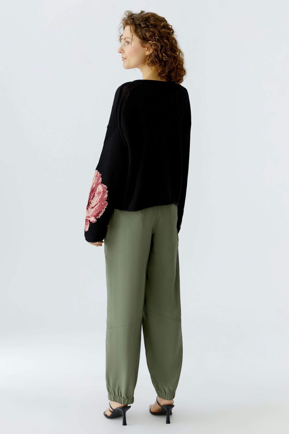 Femme portant un chandail imprimé floral avec motif expressif sur la manche et encolure arrondie, vue arrière.