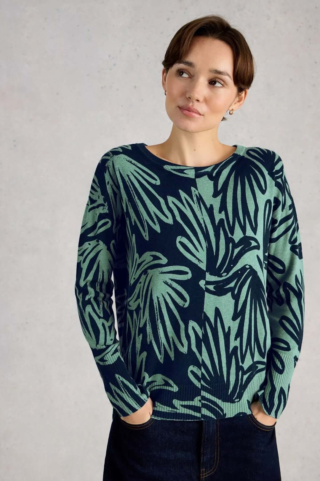 Femme portant un chandail imprimé à manches longues Olive avec un design graphique subtil. Mode décontractée et élégante.