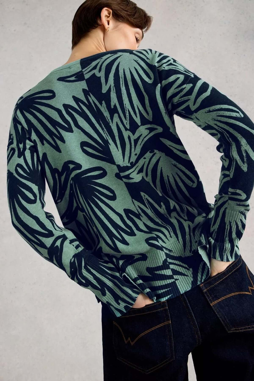 Chandail imprimé à manches longues Olive avec un motif graphique, manches longues, encolure ronde, porté avec un pantalon foncé.