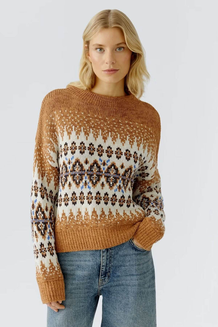 Femme portant un chandail jacquard à motif nordique, col montant côtelé, coupe ample, tricoté pour chaleur et style décontracté.