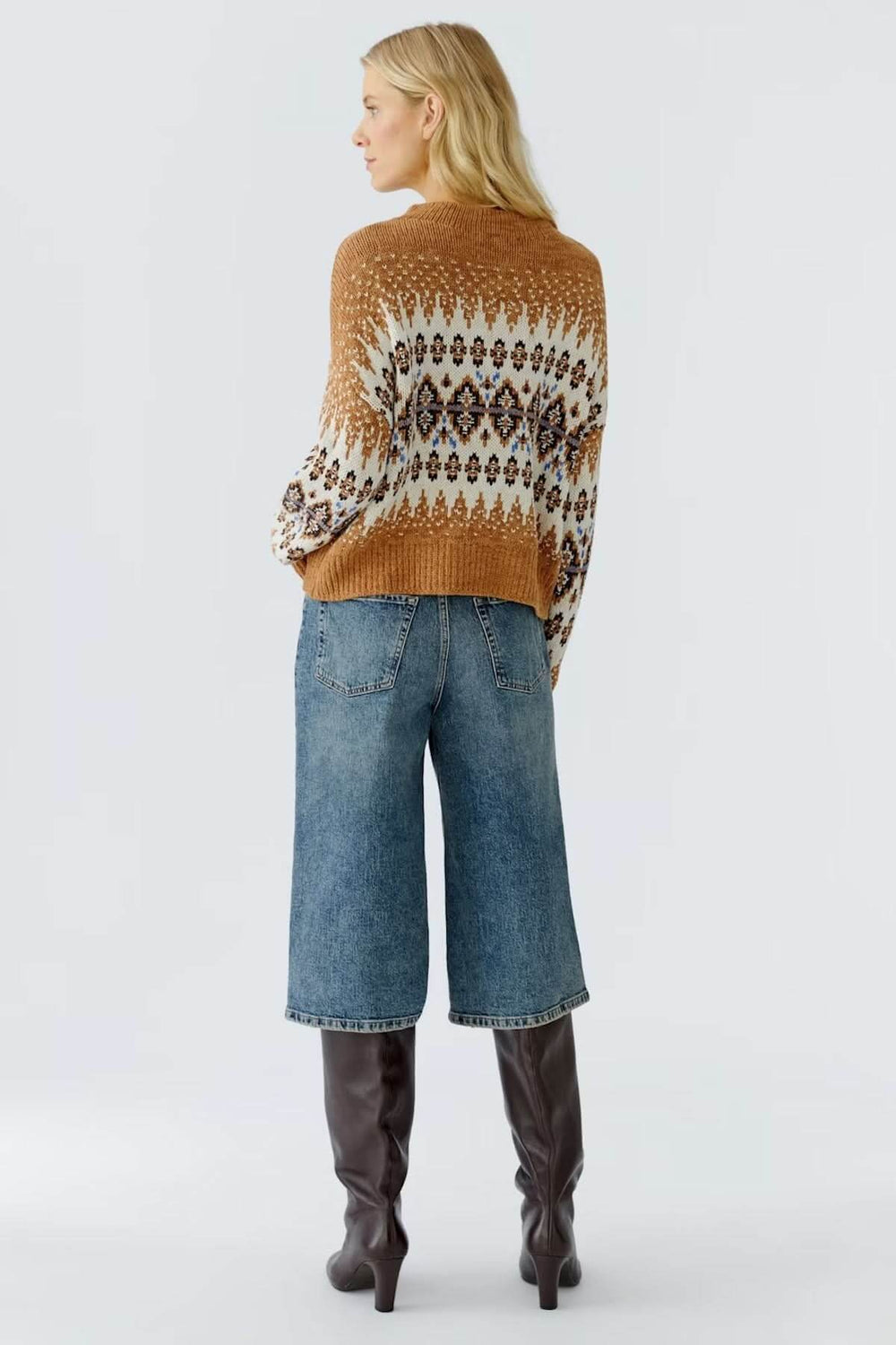 Femme portant un chandail jacquard à motif nordique avec jeans et bottes, vue de dos. Chandail jacquard à motif nordique moderne.