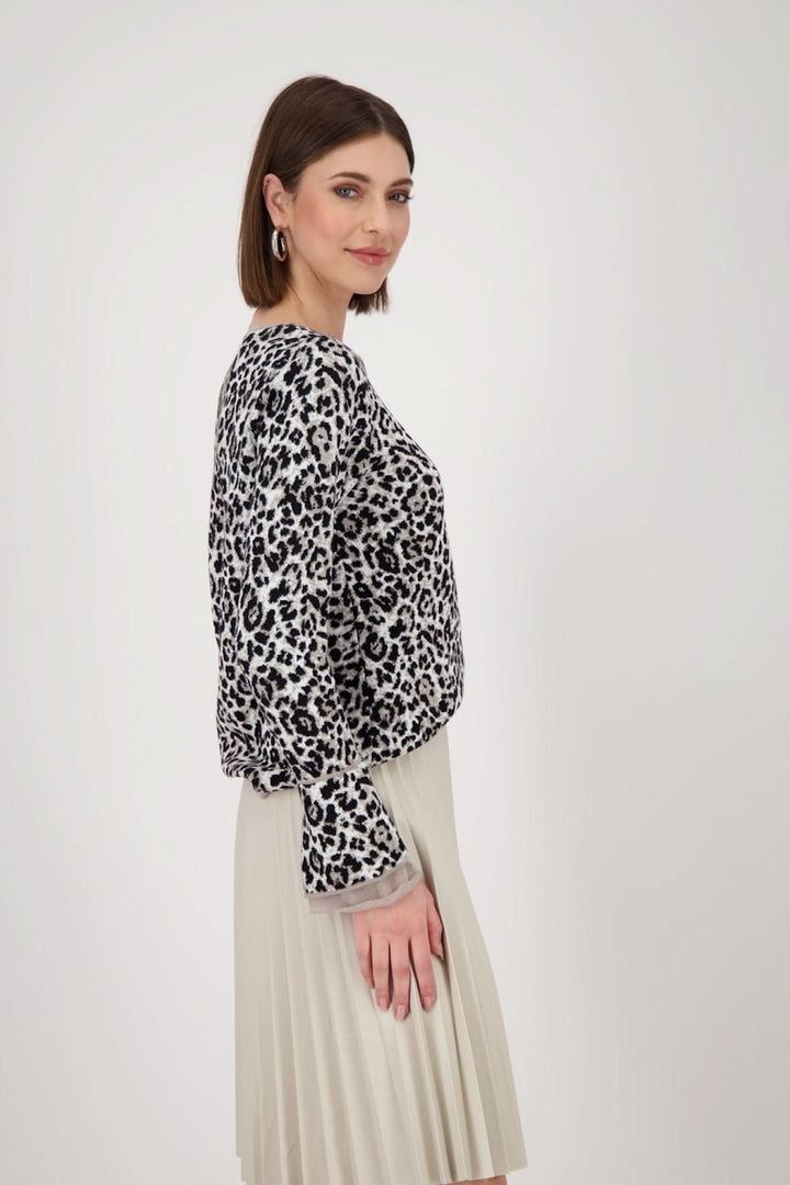 Chandail à manches longues noir et blanc à imprimé léopard, porté avec une jupe plissée élégante.