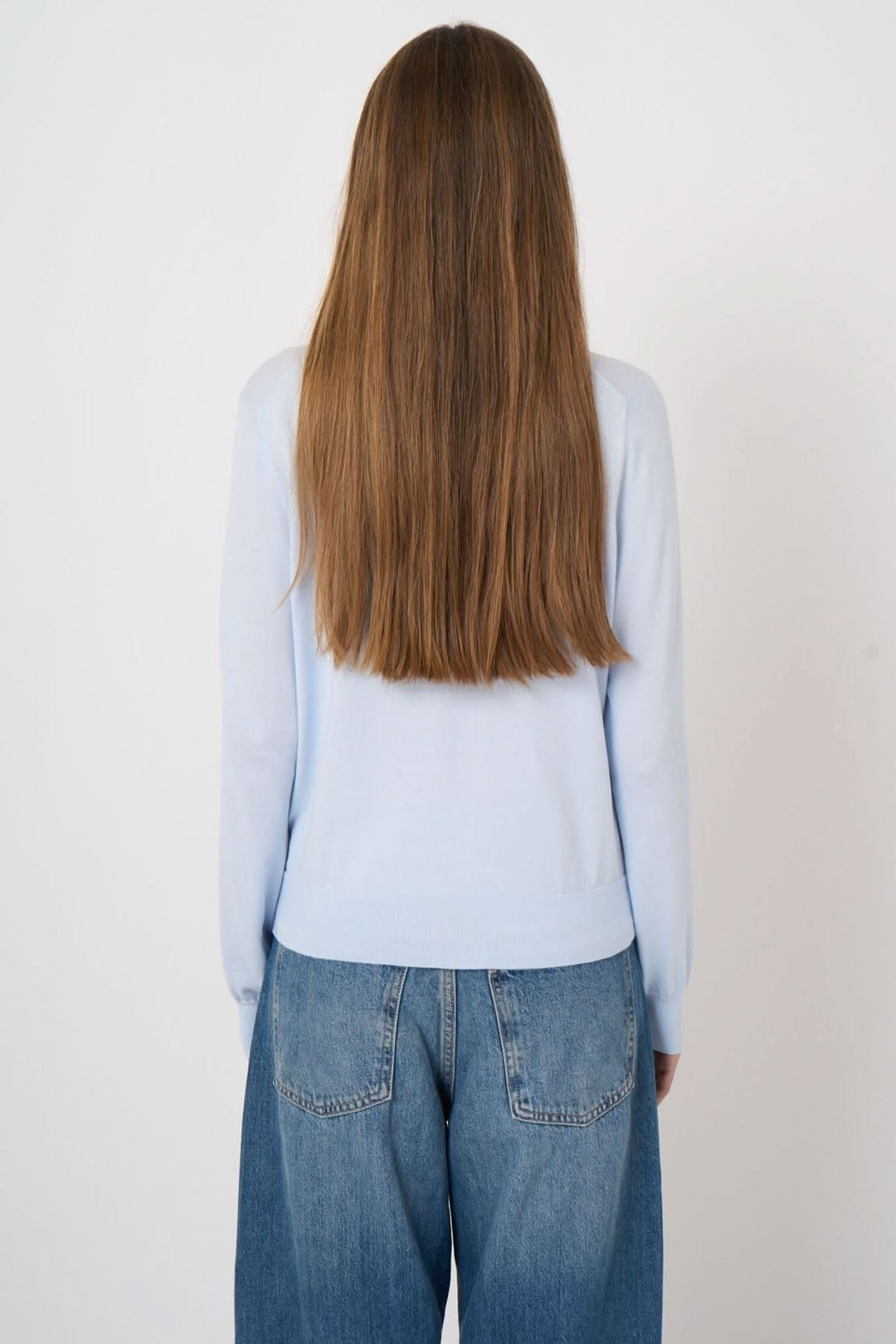 Femme portant un chandail à manches longues bleu, coupe droite, vue de dos avec jean casual, tissu doux et confortable.