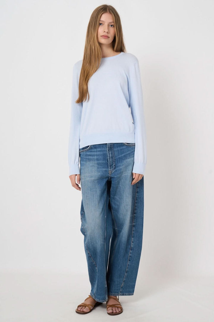 Femme portant un chandail à manches longues bleu clair avec un jean, confort et style décontracté pour le quotidien.