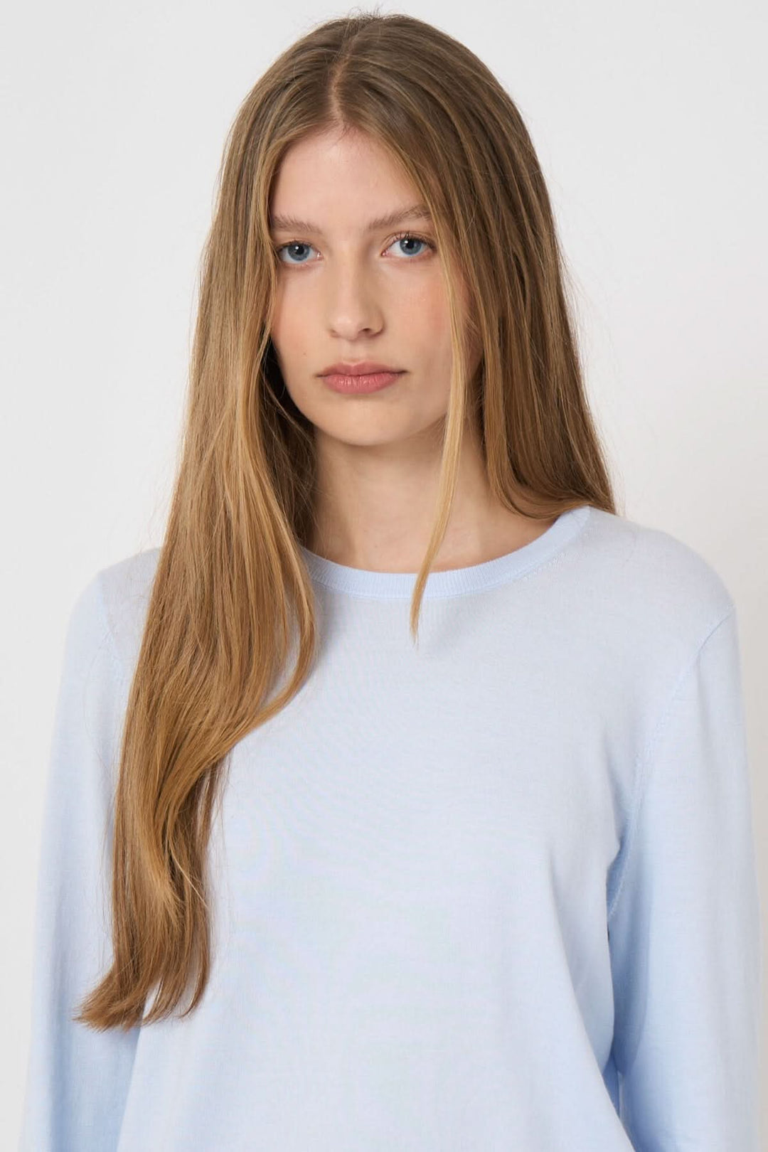 Chandail à manches longues en tissu doux avec encolure ronde et coupe droite, porté par une femme, idéal pour un look quotidien élégant.