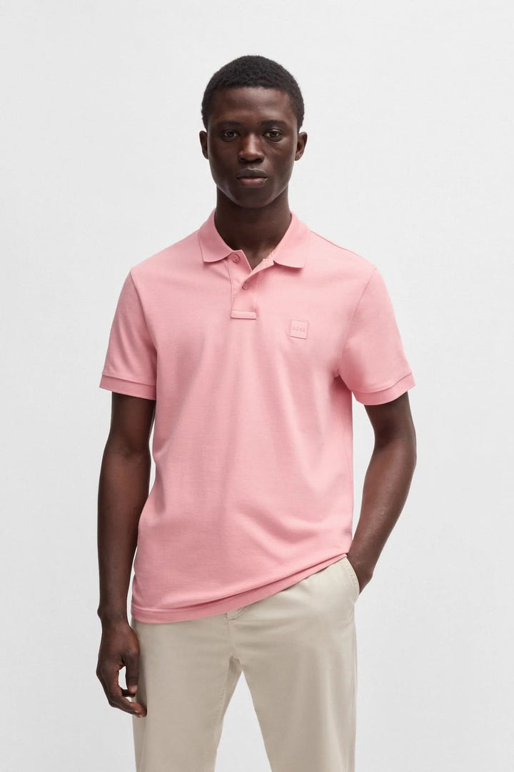 Polo classique rose BOSS avec logo ton sur ton, manches courtes et col à deux boutons, porté par un homme.