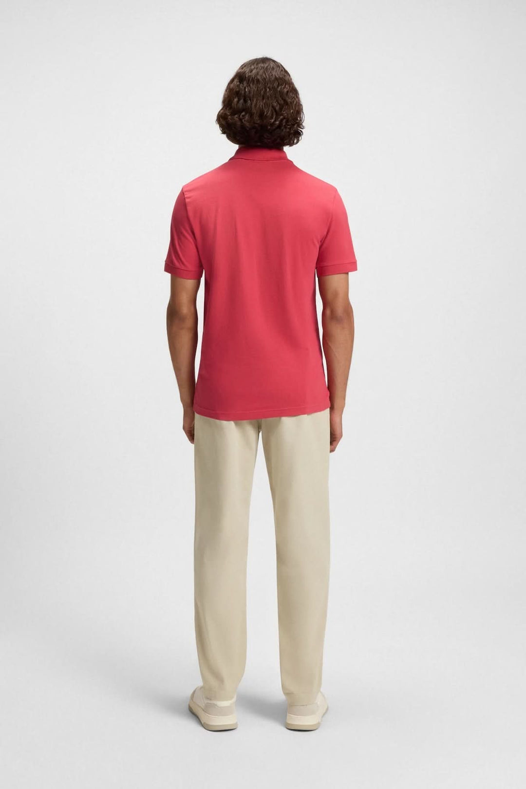 Homme de dos portant un polo rouge BOSS avec pantalon beige, dégageant une allure casual-chic.