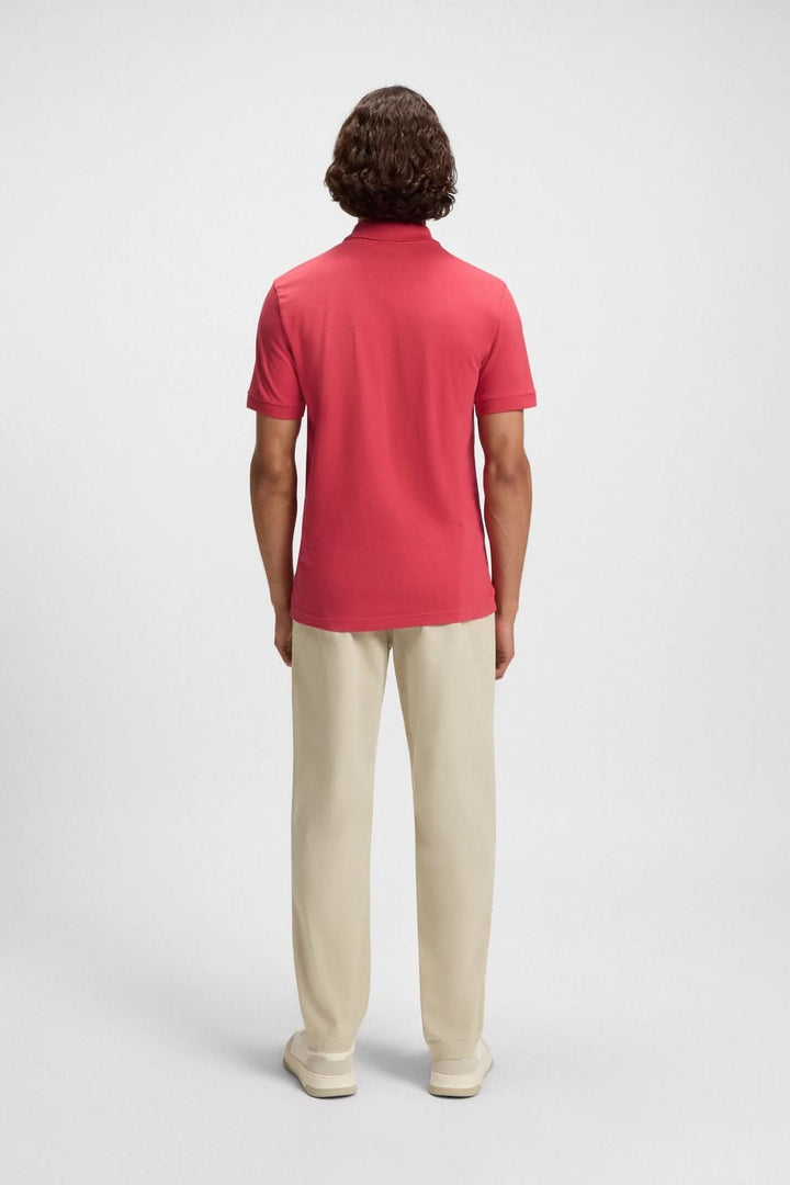 Homme de dos portant un polo rouge BOSS avec pantalon beige, dégageant une allure casual-chic.
