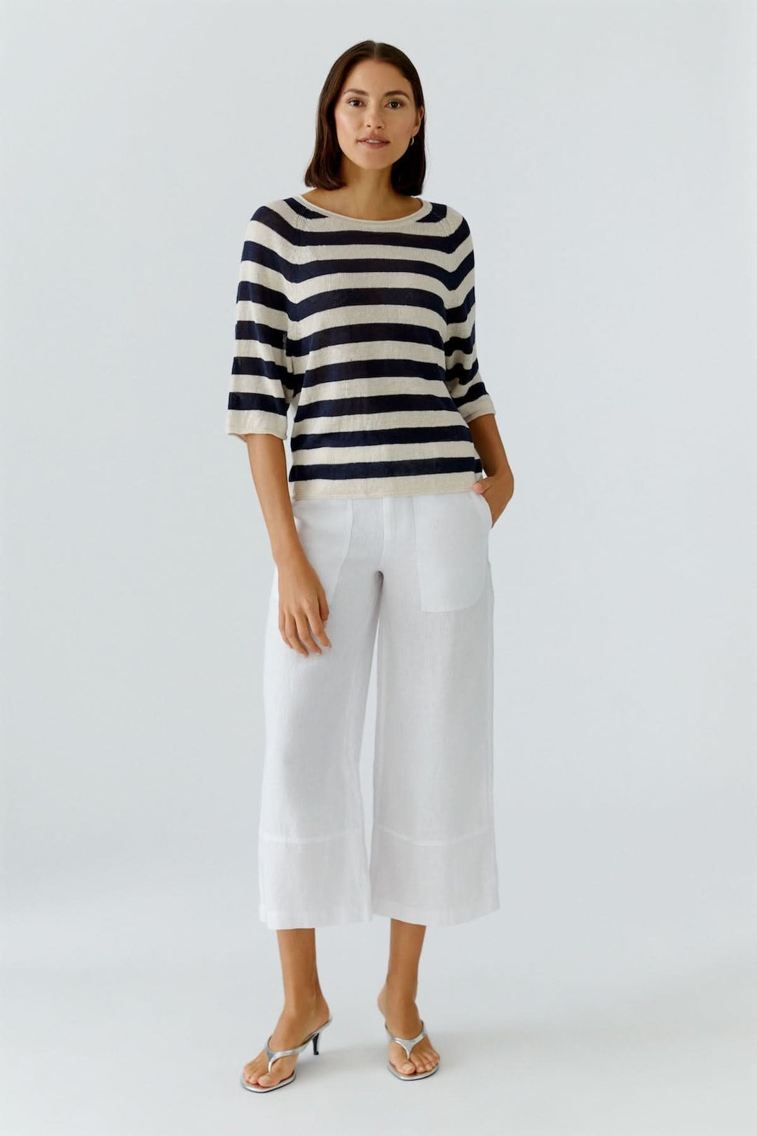 Femme portant un chandail à rayures texturées manches trois-quarts avec un pantalon blanc élégant.