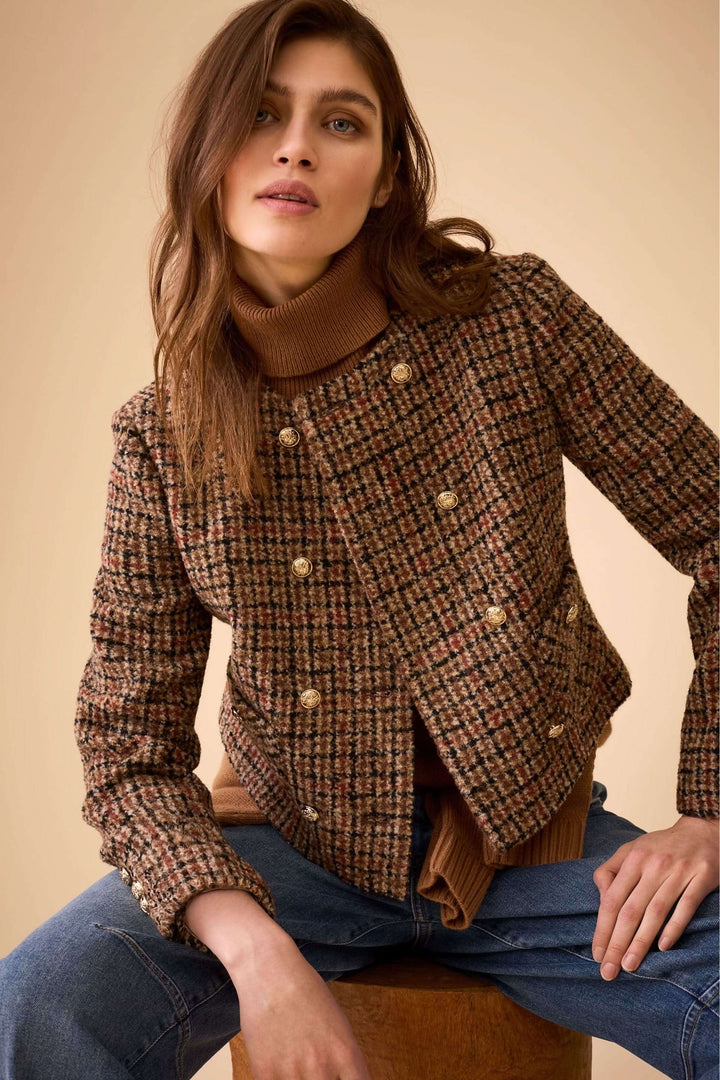 Modèle portant un chandail sans manches à col roulé, dos ajouré, sous une veste à carreaux chic, style minimaliste.