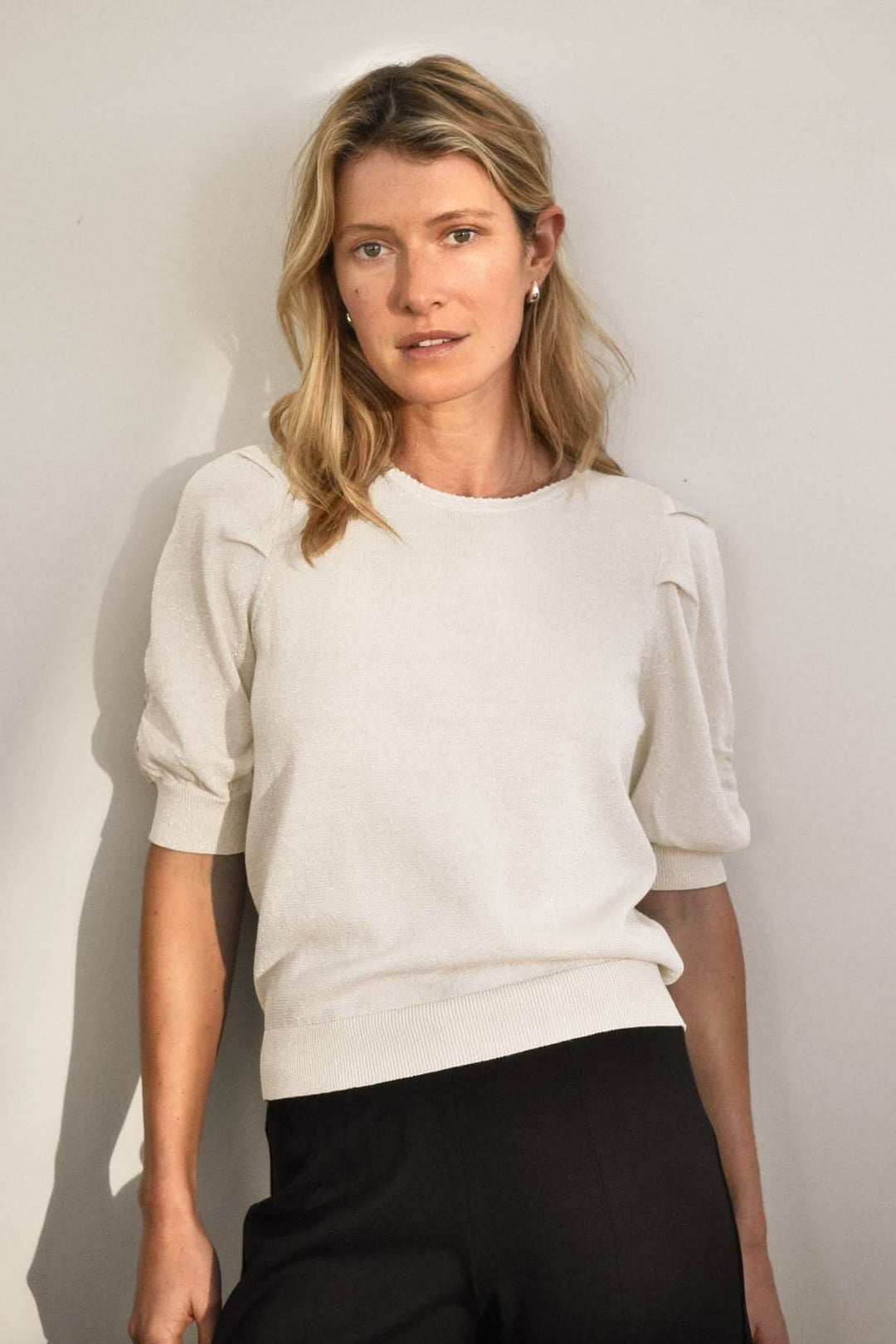 Chandail scintillant Varaia à manches courtes et encolure ronde, porté par un modèle dans un cadre élégant.