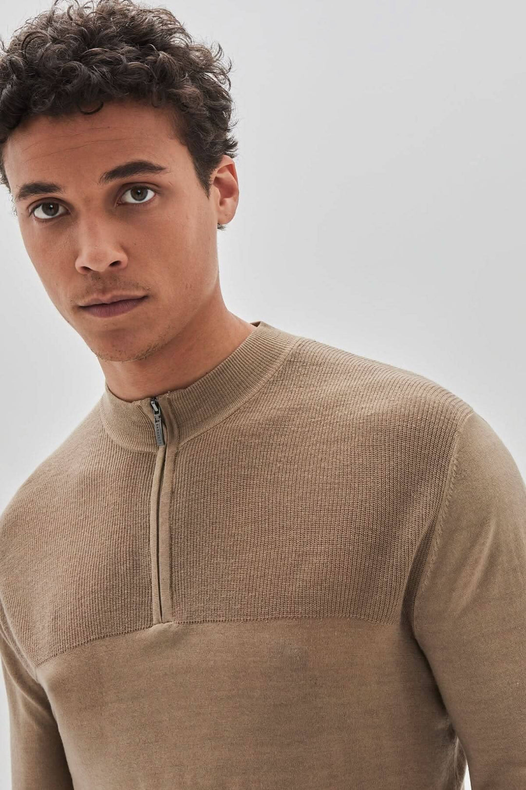 Homme portant un chandail zippé Newbury en laine mérinos, couleur beige, avec un design élégant.