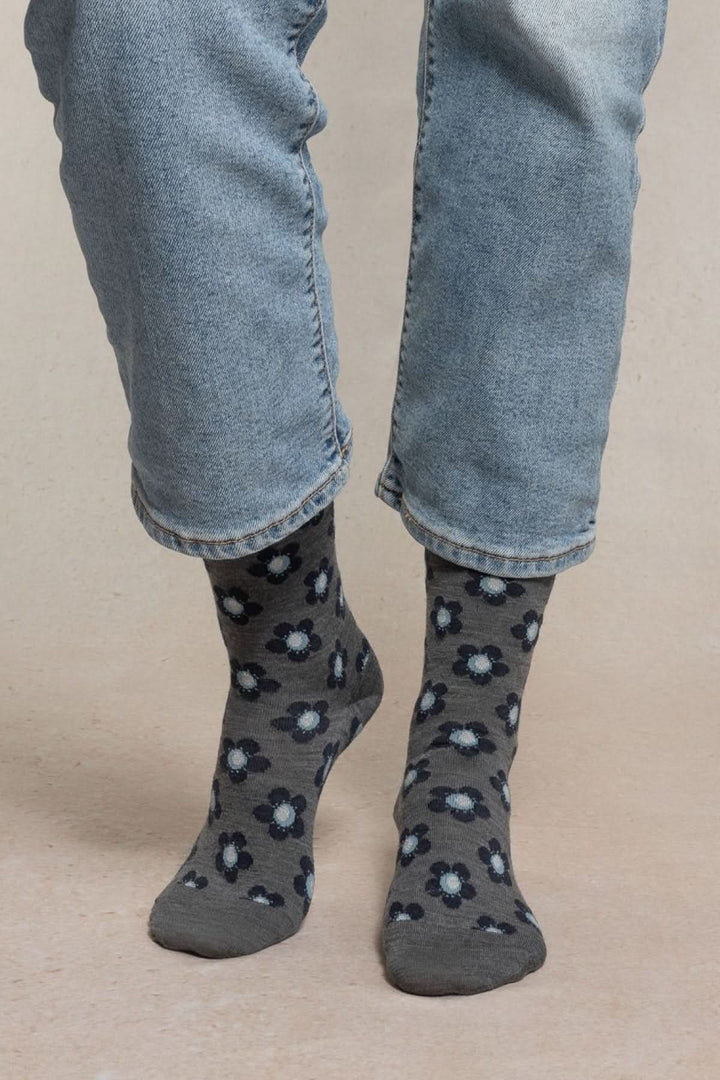 Chaussettes en maille à petit motif floral grises et bleues portées avec un jean, style casual et confortable.