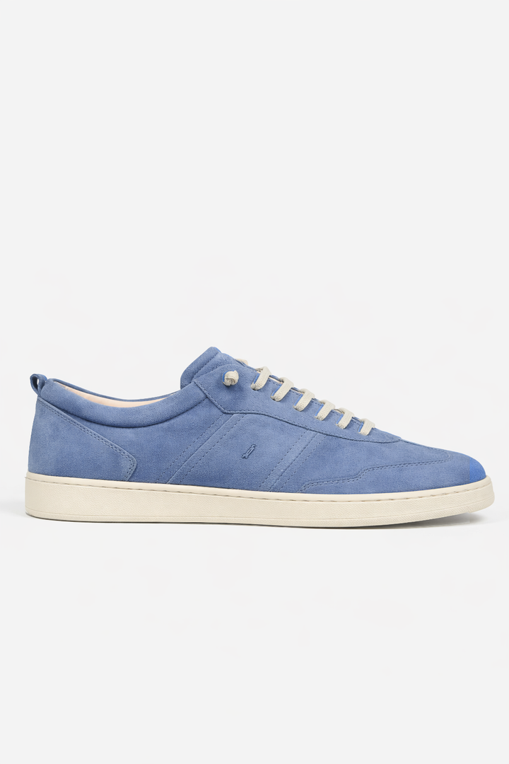 Chaussure en cuir suédé bleue avec design épuré sur semelle blanche contrastante, chic et décontractée.
