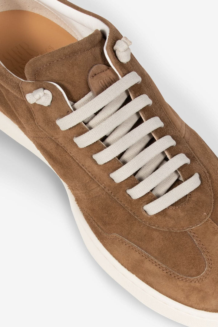 Chaussure en cuir suédé marron avec lacets blancs et semelle contrastante, design élégant et contemporain.