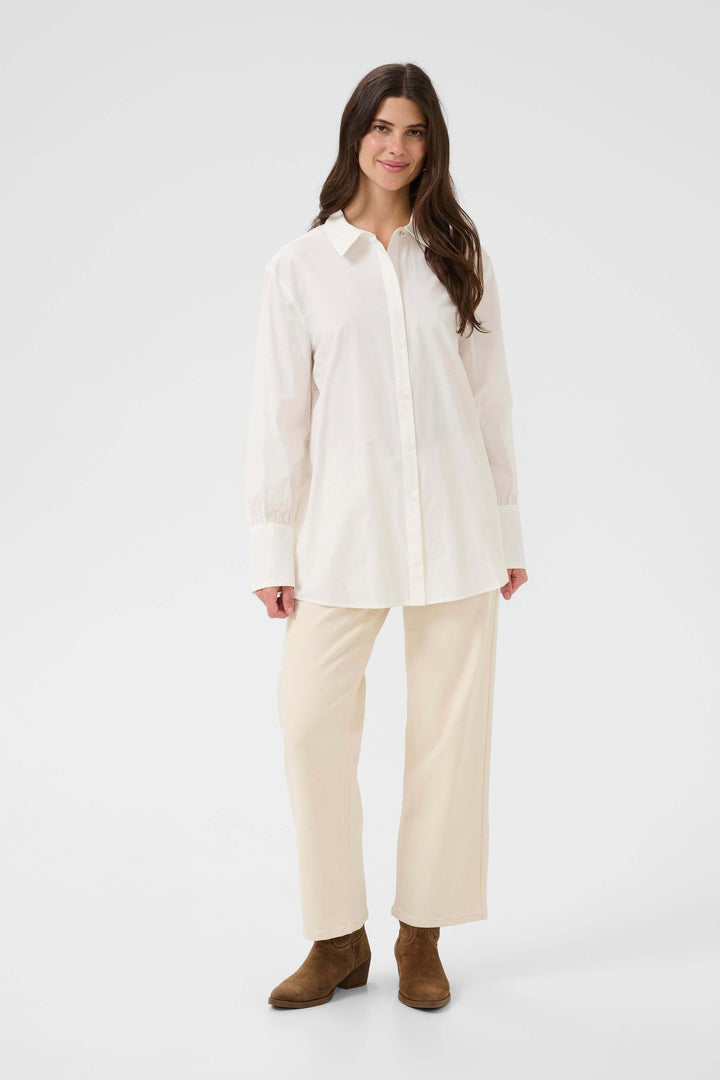Femme portant la Chemise Alison élégante et fluide en blanc, avec col classique et coupe décontractée.