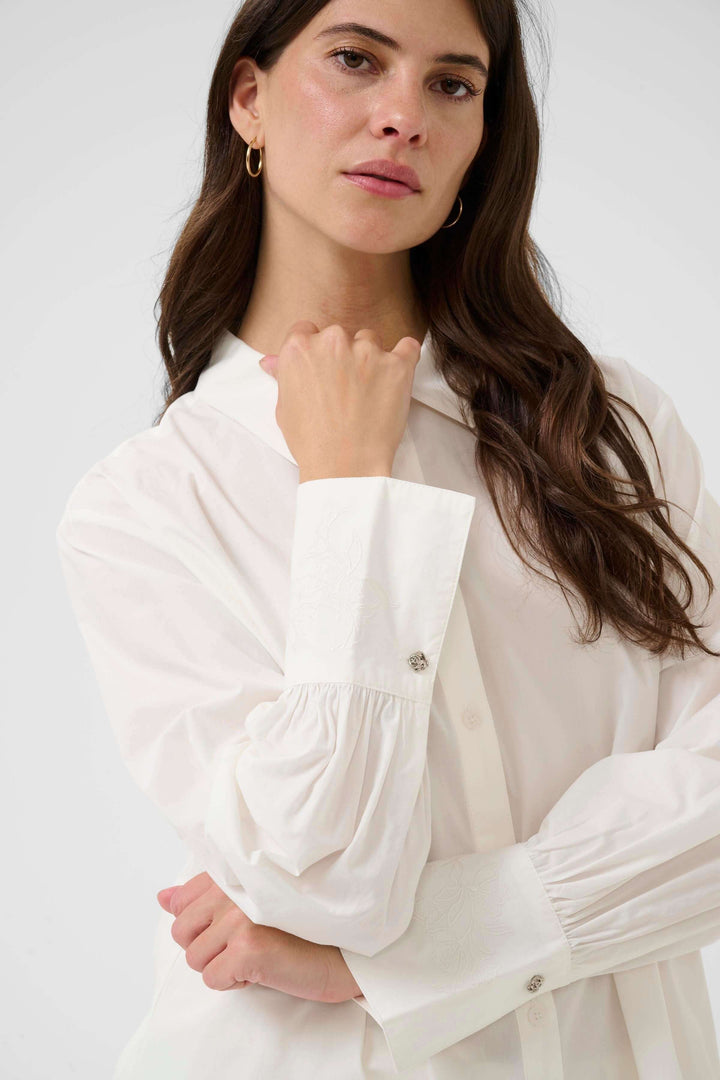 Femme portant la Chemise Alison blanche élégante avec col classique et manche fluide, idéale pour le bureau ou un look décontracté.