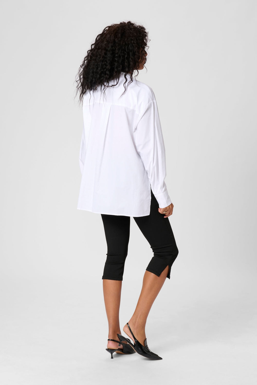 Vue arrière d'une chemise Mira blanche ample, portée avec un legging noir, détail chic au col.