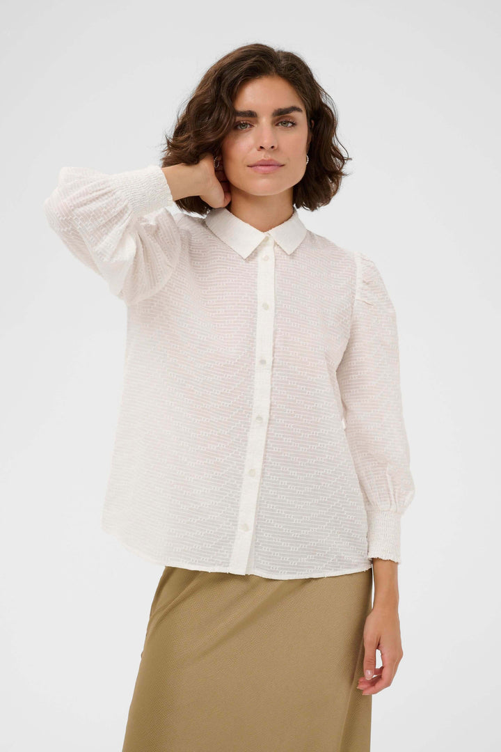 Femme portant la Chemise Penelope texturée à manches bouffantes avec col chemise et poignets smockés, style moderne et féminin.