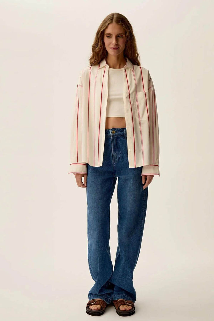 Femme portant une chemise blanche rayée Ulysse avec un jean, style chic et décontracté.