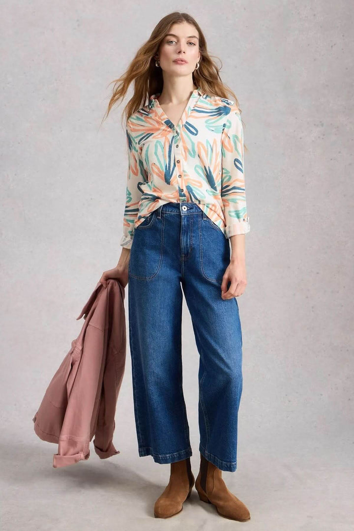 Femme portant une chemise boutonnée col en V manches trois-quarts Annie avec un jean évasé, tenue décontractée et élégante.