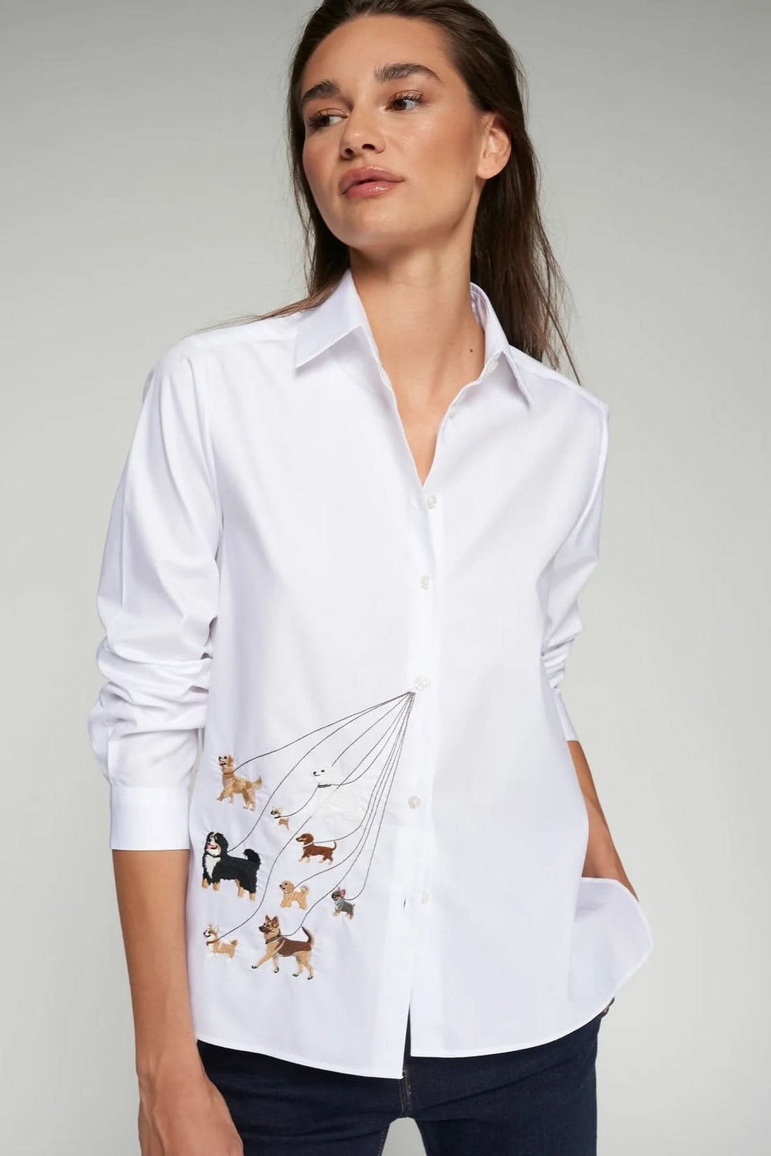 Femme portant une chemise brodée de chiens avec manches longues et coupe droite, détail de broderie ludique et élégante.